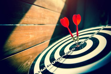 Hedef tahtası ya da dart tahtası kırmızı ok atarak, iş hedefleri ve kazanma hedefleri için güneş ışığı ve gölgelerle bir atışın merkezini vuruyor.