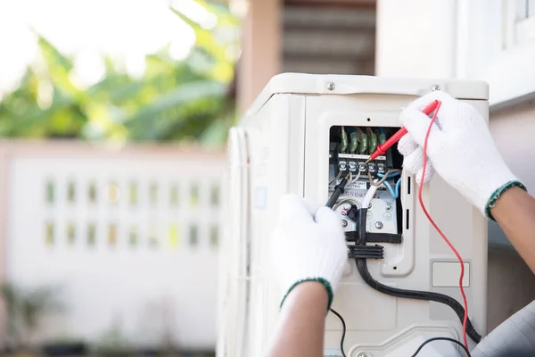 Teknisyen elini, kurulum ve havalandırma hizmetlerinin bakımı sonrasında açık hava kompresör ünitesinde elektrik akımını kontrol eden ölçüm ekipmanları kullanarak kapat.