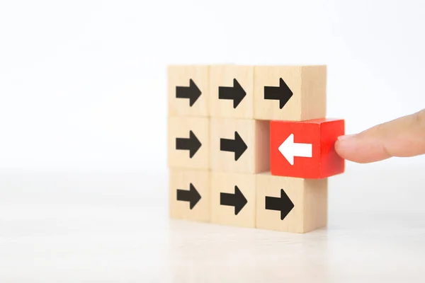 特写手拿着方块木玩具堆放箭头图标指向相反的方向 为企业变革领导者规划公司和变革理念指明方向 — 图库照片