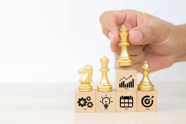 ビジネスチームの成長と組織管理戦略計画のグラフアイコンの概念で積み上げ木製のおもちゃのブロックに王のチェスを手を選択 ロイヤリティフリーのストック写真