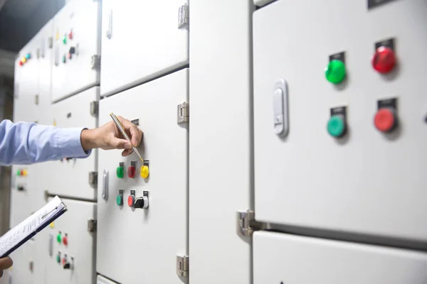 Electrical engineer checking electrical voltage at circuit breaker air handling unit (AHU) starter control panel for air conditioner load center cabinet for maintenance power system distribution.