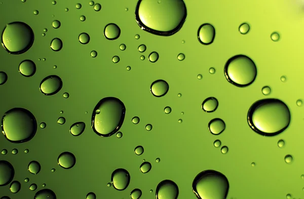 Water drops against a glowing green background — Stock Photo, Image