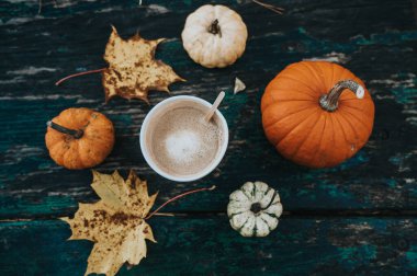 Sonbahar yatağı. Karton bardakta kahve. Balkabağı. Akçaağaç yaprakları. Eski ahşap masa.