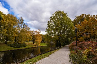 Kanalı ve kaldırımı olan sonbahar parkı. Bulutlu bir gün. Riga, Letonya.