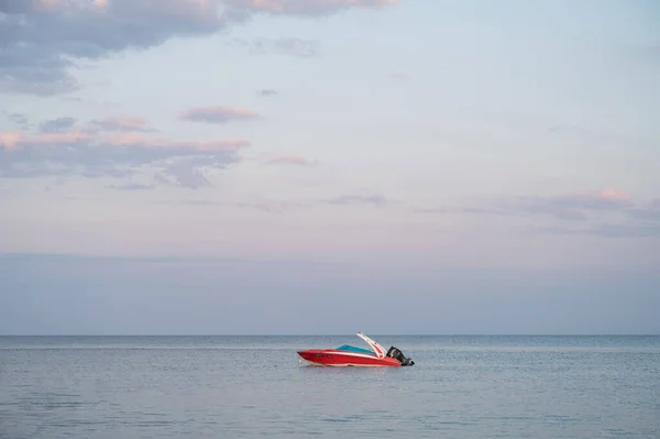 Small red motor boat in the sea. Twilight sky and sea.