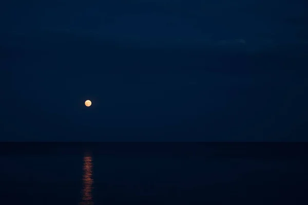 Night landscape. Full moon over the sea. Reflection of the moon path.