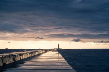 Scenic landscape of sunset over Baltic sea. Cloudy sky. Mangalsala mols. Way to lighthouse. Dramatic seascape.