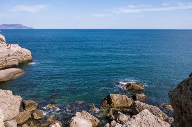 Scenic landscape of blue sea, cloudy sky. Huge rocks and stones on beach. Beautiful nature.