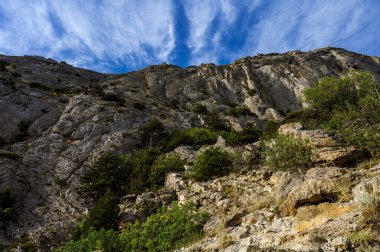 Bottom view of huge rock. Clouds in blue sea. Mountain.