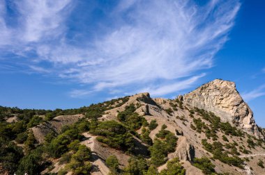 Bottom view of huge rock. Clouds in blue sea. Mountain.