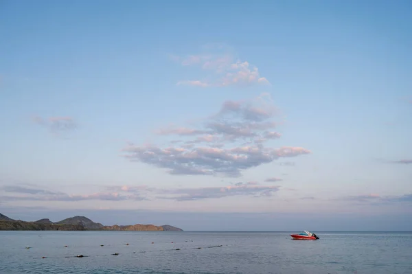 Small red motor boat in the sea. Twilight sky and sea.