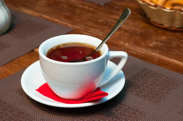 Uma xícara branca de chá em um pires, um guardanapo vermelho. — Fotografia de Stock