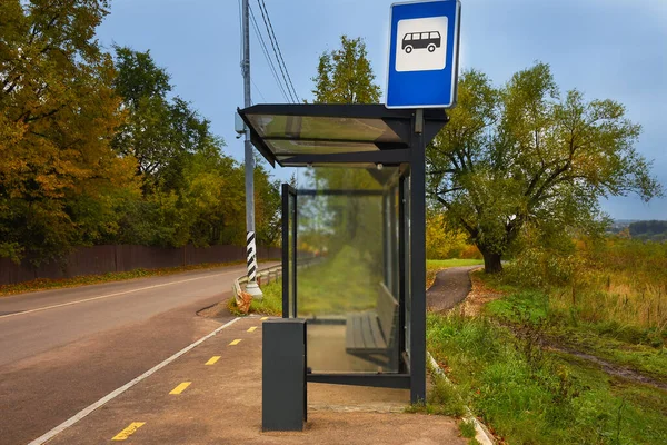 Sonbahar günü yol kenarındaki otobüs durağında insanlar yoktu. Yol kenarında bank olan boş bir otobüs durağı. Ulaşım konsepti. Otobüs durağı arka planı. Hiç kimse. cam toplu taşıma durağı