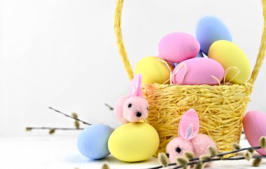 Paskalya sepeti renkli yumurtalarla dolu, yumurtaların üzerinde sevimli tavşanlar oturuyor..