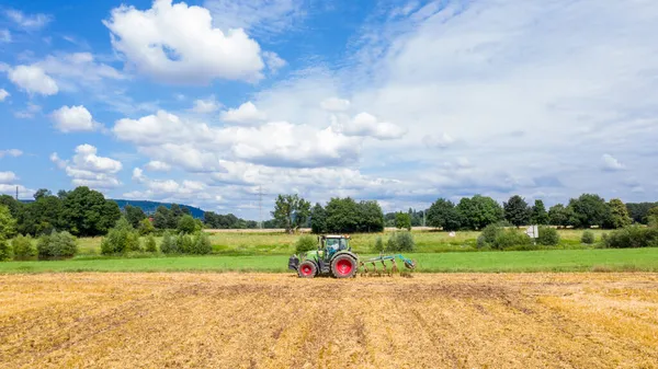 Een Landbouwtrekker Die Een Geoogst Veld Kweekt Tegen Een Blauwe — Stockfoto