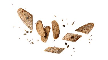 Dilimlenmiş taze ekmek tam tahıllı baget ekmeği balkabağı, ayçiçeği ve keten tohumları beyaz arka planda izole bir şekilde uçuşuyor. Sağlıklı hamur işleri.