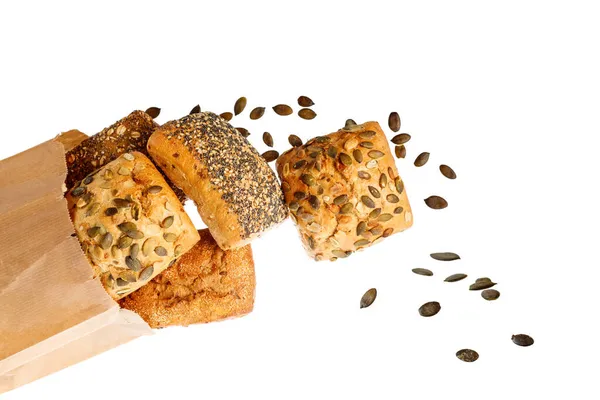 新鲜的烤面包卷 用罂粟和南瓜籽做的特写从白色背景的纸包装上掉下来 生锈的面包在飞 — 图库照片