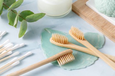 Kokulu okaliptüs dallı doğal banyo aksesuarları. Bambu ahşap diş fırçaları açık yeşil mermer arka planda yakın plan. Sıfır atık, bedava plastik konsept