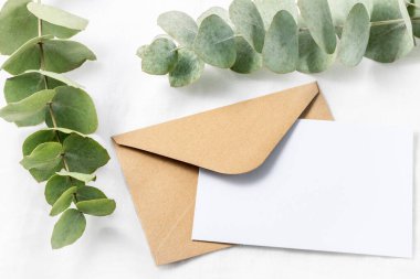 Beyaz keten arka planda aromalı okaliptüs dalları olan eski kahverengi bir zarf. Düğün ya da doğum günü kartpostalının fotokopi alanı ile kutlanması