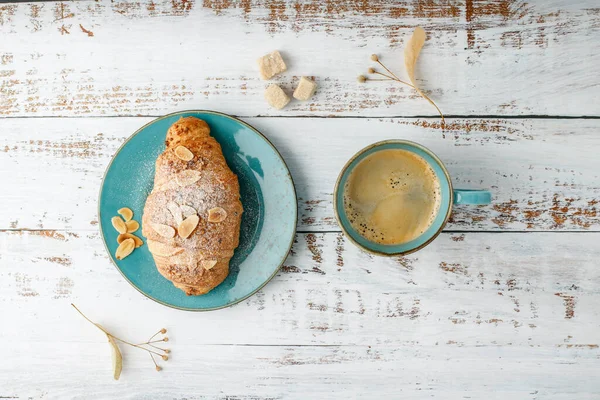 新鲜的烤杏仁早餐羊角面包在老式绿松石盘和热咖啡杯在乡村木背景 顶部视图糕点早上好卡与复制空间 — 图库照片