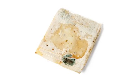 Çürük keçi peyniri dilimlerinde beyaz, yeşil ve siyah küfler. Bozuk keçi peyniri ve beyaz arka planda izole edilmiş çemen otu tohumları. Küf üzerine seçici odak