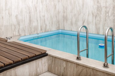 Açık gri saunanın içinde modern küçük bir yüzme havuzu. Sağlık hizmetleri yaşam tarzı.