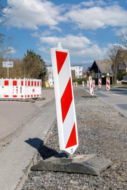 Yol çalışıyor. Kırmızı ve beyaz çizgili yol işaretleri yakın..