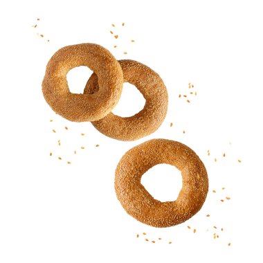 Beyaz zemin üzerinde susamlı uçan üç geleneksel Türk simit simitleri. 