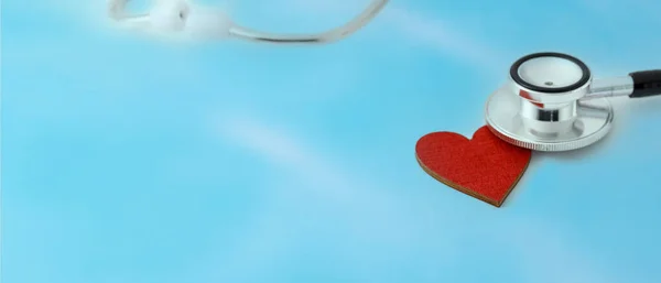 ぼやけた青の白い背景に赤い心臓に聴診器の頭 健康な心臓の日 心臓病の概念 コピースペース付きライトバナー — ストック写真