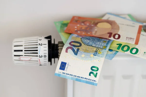 Euro money banknotes on the heating radiator with temperature control regulator. Selective focus on 20 euro banknote. Expensive and rising heating costs and savings energy concept