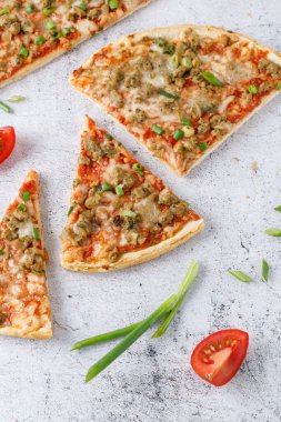 Taze pişmiş ve dilimlenmiş ton balıklı pizza, peynirli, domates soslu ve yeşil soğanlı retro taş zemin. Sağlıklı yemek..