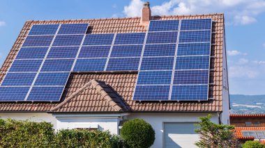 House with solar panels attached to the roof on sunny day. New eco technology of electricity generation. Alternative electrical energy source concept.