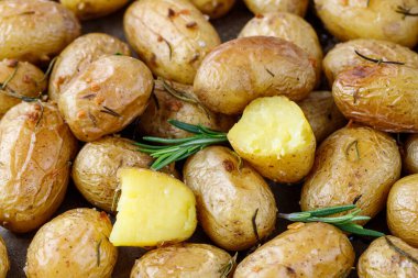 Taze pişmiş küçük sarı zeytinyağı, biberiye ve fırın tepsisinde sarımsaklı patates..