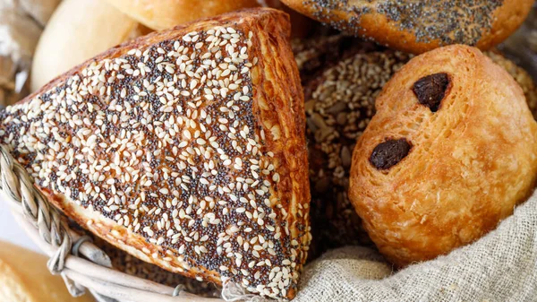 新鲜的烤油酥糕点面包 用罂粟和芝麻种子包裹在面包篮子里 Lye椒盐面包 — 图库照片