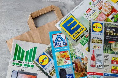  Almanya - 02 Ekim 2022: Edeka, Lidl, Aldi ve Marktkauf süpermarket broşürleri ve kağıt alışveriş çantası.