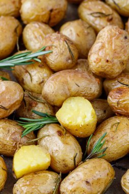 Taze pişmiş küçük sarı biberiyeli patatesler ve fırın tepsisinde sarımsak..