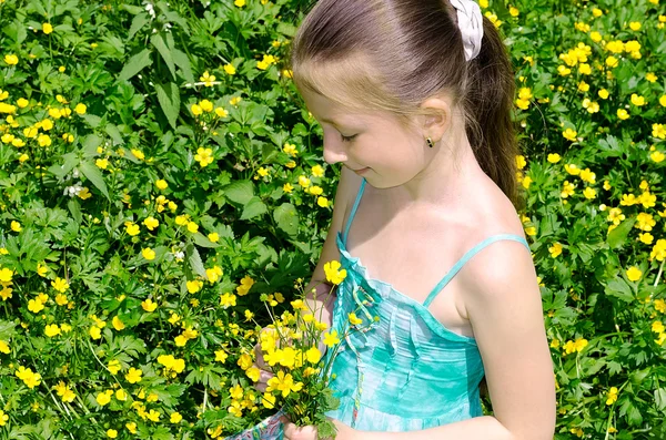 The child sits on a glade and holds flowers — Stock Photo, Image