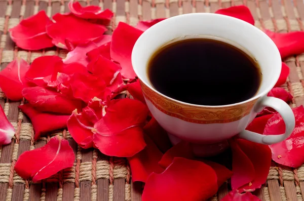 Kopje koffie en bloemblaadjes van rozen — Stockfoto