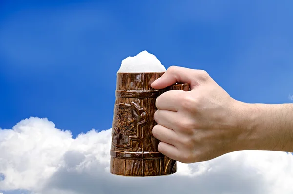 Vaso de cerveza en una mano contra el cielo — Foto de Stock