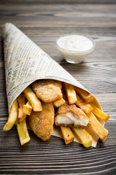 Peixe e batatas fritas na mesa de madeira — Fotografia de Stock