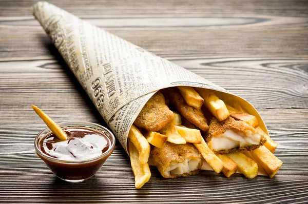 Pescado y patatas fritas en mesa de madera — Foto de Stock