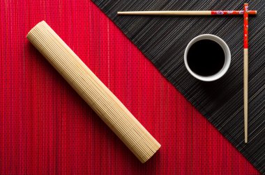 Yemek çubukları ve bambu hasır üzerinde soya sosu ile kase