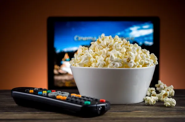 Popcorn and a remote control for the TV background — Stock Photo, Image