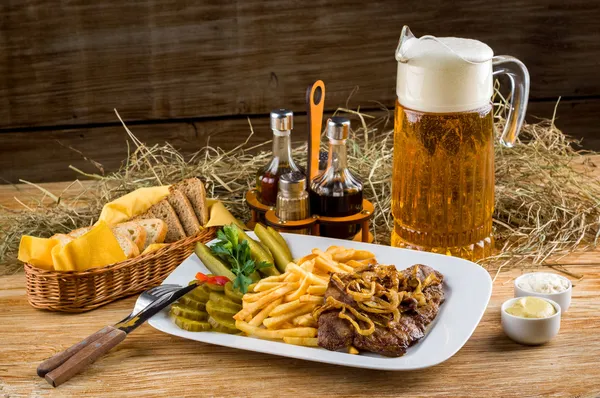 Roast beef, french fries and jug of beer — Stock Photo, Image