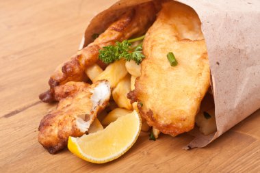 Kağıt ahşap bir masa üzerinde balık ve patates kızartması dedim