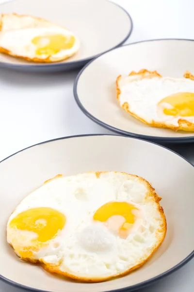 Cuatro huevos fritos en tres platos —  Fotos de Stock