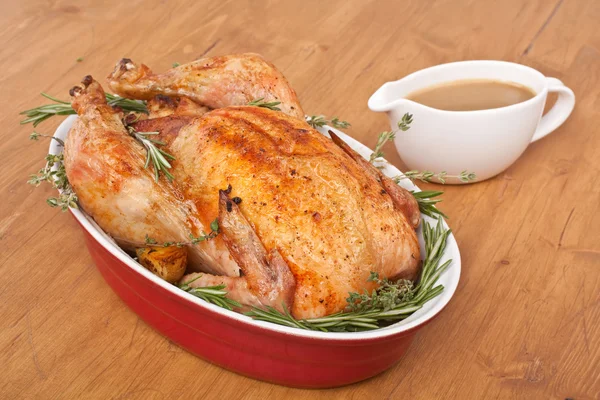 Whole roasted stuffed turkey in a dish with gravy — Stock Photo, Image