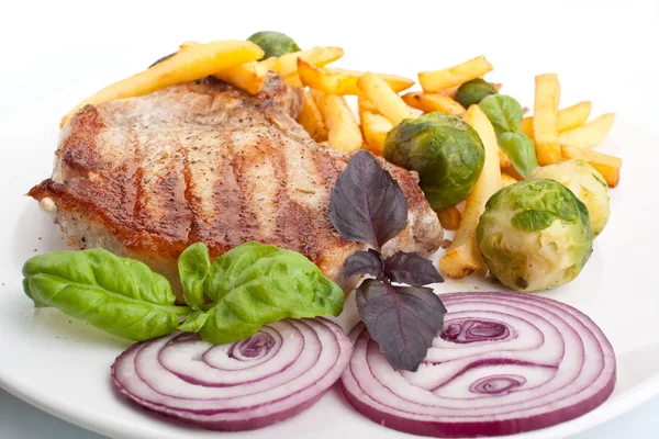 Chuletas de cerdo con patatas fritas y coles de Bruselas — Foto de Stock