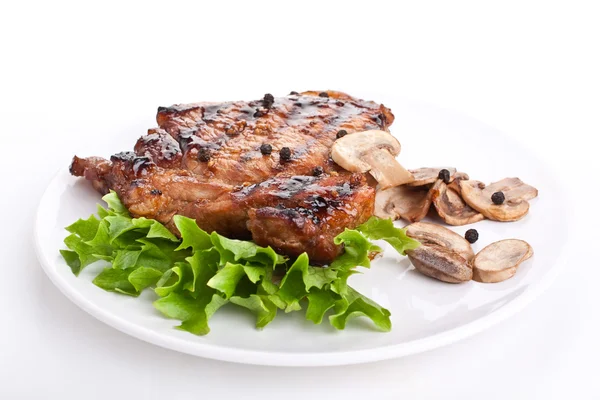 Eine Portion Schweinekotelett garniert mit Pilzen und Salat — Stockfoto