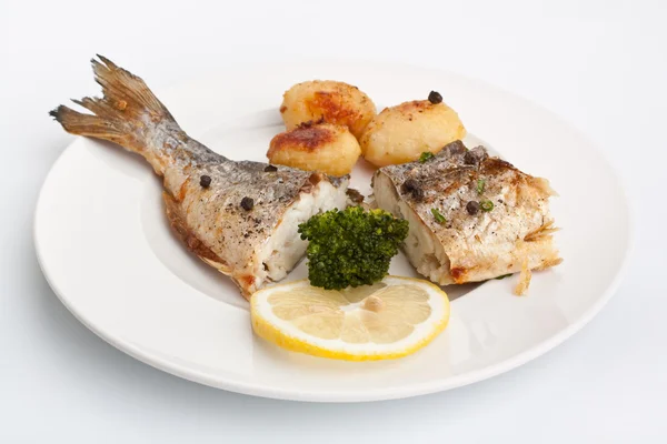 Zeebrasem vis met groenten op wit bord — Stockfoto